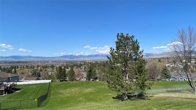 surrounding community with a lawn, a mountain view, and fence