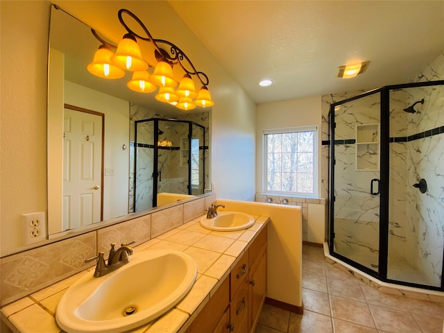 full bathroom with a sink, a marble finish shower, tile patterned flooring, and double vanity