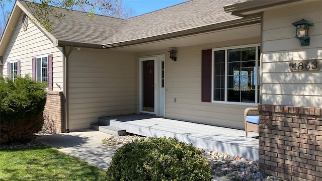 entrance to property with brick siding and roof with shingles