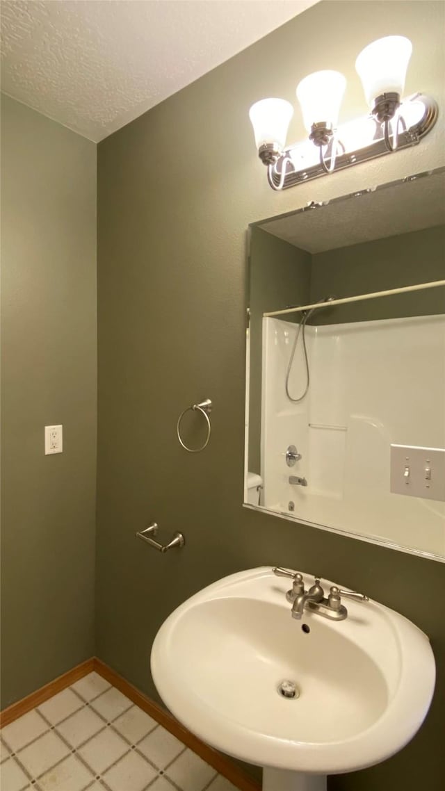 bathroom with a sink, baseboards, and a textured ceiling