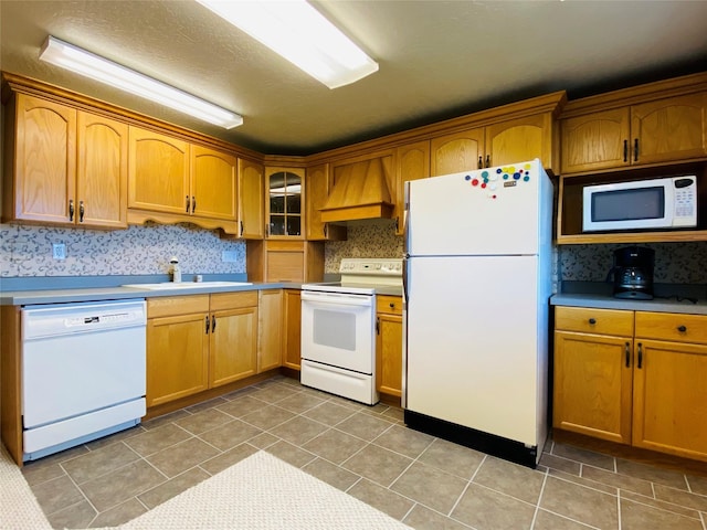 kitchen featuring decorative backsplash, a sink, premium range hood, white appliances, and light tile patterned flooring