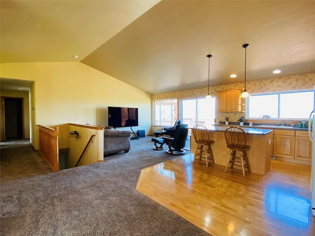 living area with a healthy amount of sunlight, light carpet, light wood finished floors, and lofted ceiling