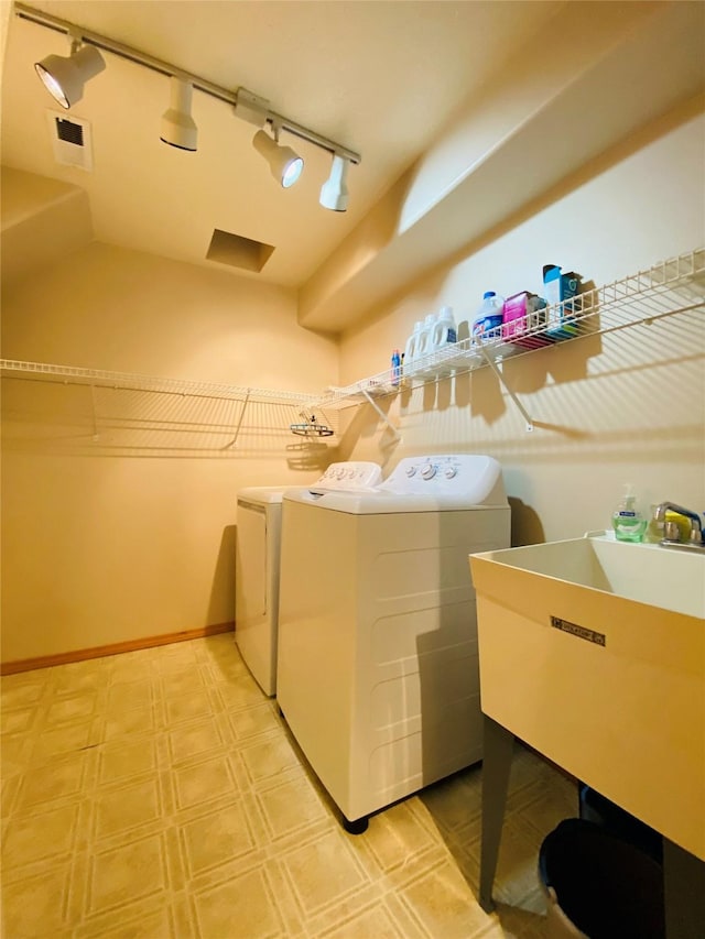washroom featuring laundry area, a sink, washer and dryer, and rail lighting