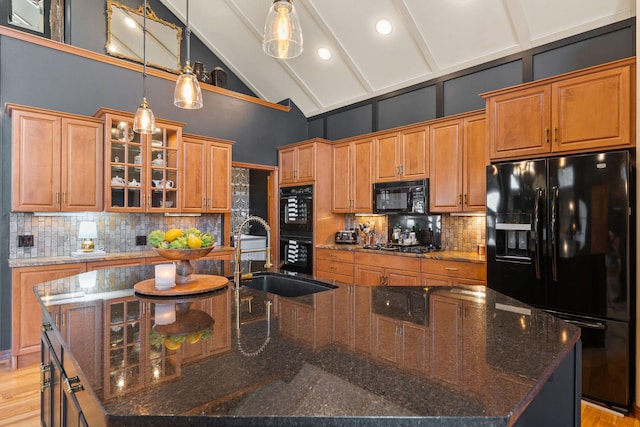 kitchen with decorative backsplash, a spacious island, a sink, high vaulted ceiling, and black appliances