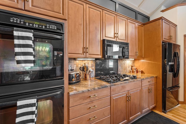 kitchen featuring tasteful backsplash, light stone countertops, black appliances, lofted ceiling, and dark wood-type flooring