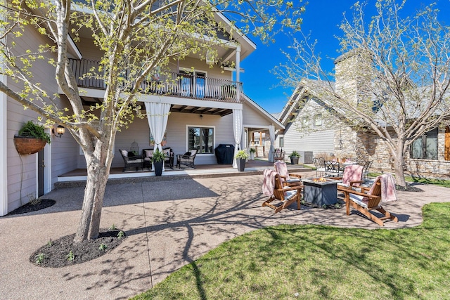 rear view of house with a lawn, a fire pit, a patio area, and a balcony