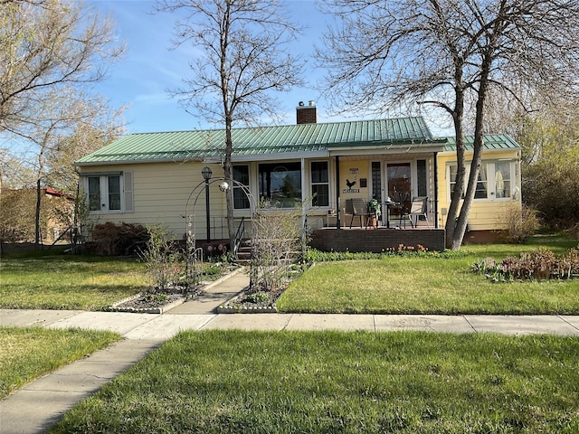 ranch-style house with a chimney, a porch, metal roof, and a front yard