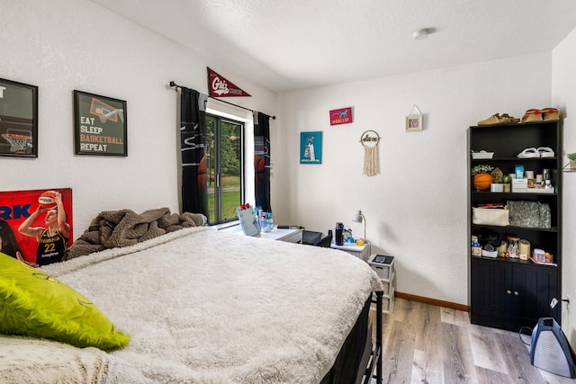 bedroom featuring access to outside, baseboards, and wood finished floors
