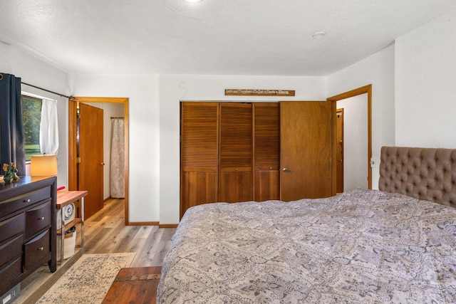 bedroom with a closet, baseboards, and wood finished floors