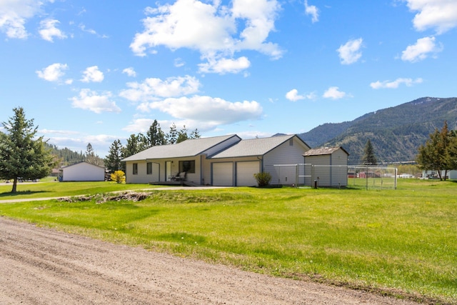 single story home with a garage, fence, a mountain view, and a front lawn