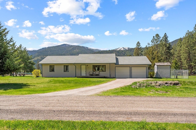 ranch-style home featuring an attached garage, fence, a mountain view, and dirt driveway