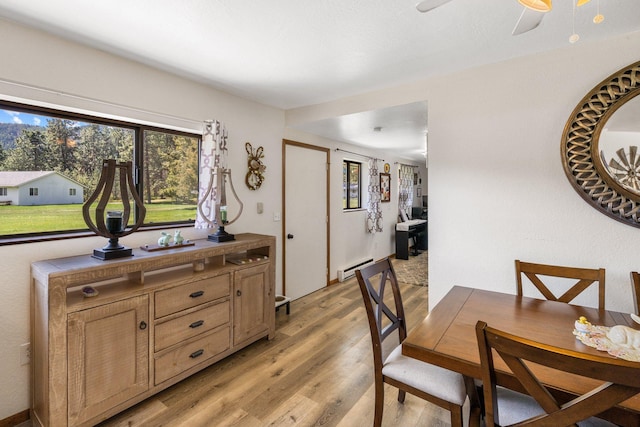 dining space featuring light wood-type flooring, a baseboard radiator, and a ceiling fan