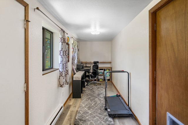 home office featuring baseboards, a baseboard radiator, and wood finished floors