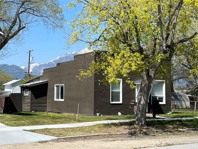 509 N 5th St, Hamilton, MT 59840 - view of property exterior featuring a lawn, a mountain view, stucco siding, and fence