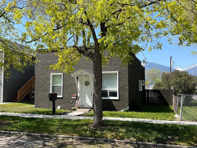 509 N 5th St, Hamilton, MT 59840 - view of front facade with stucco siding, fence, a mountain view, and a front lawn