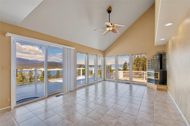 7100 Black Lake Rd, Rexford, MT 59930 - unfurnished sunroom with a wood stove, high vaulted ceiling, tile patterned flooring, plenty of natural light, and recessed lighting