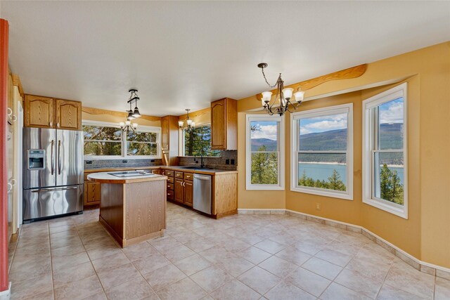 7100 Black Lake Rd, Rexford, MT 59930 - kitchen with appliances with stainless steel finishes, a chandelier, a kitchen island, backsplash, and decorative light fixtures