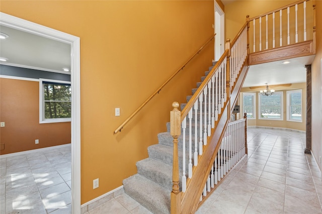 stairs featuring baseboards, ornamental molding, tile patterned floors, and a notable chandelier
