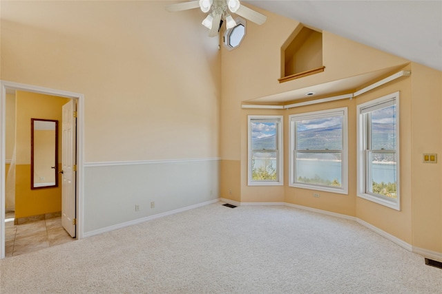 carpeted spare room featuring a towering ceiling, baseboards, a ceiling fan, and visible vents
