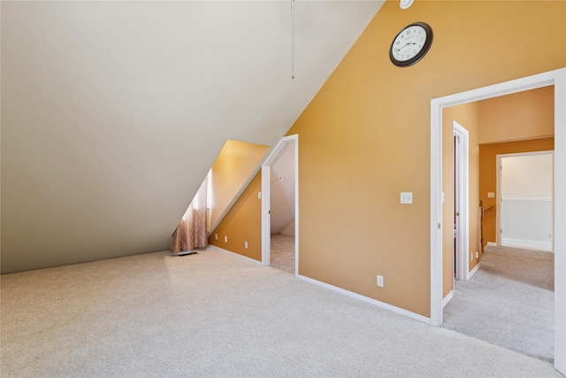 bonus room featuring light colored carpet, baseboards, and vaulted ceiling