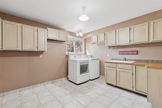 laundry room featuring independent washer and dryer, cabinet space, a sink, light tile patterned floors, and baseboards