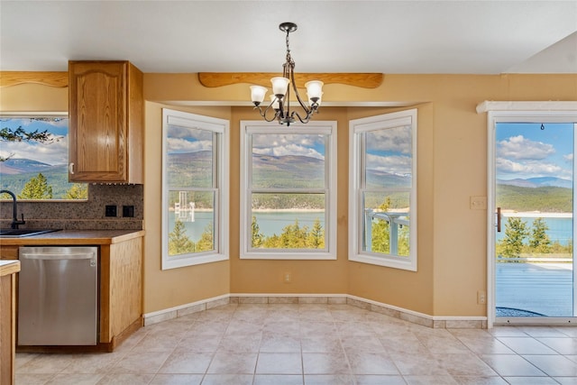 unfurnished dining area featuring light tile patterned floors, baseboards, a sink, and a notable chandelier