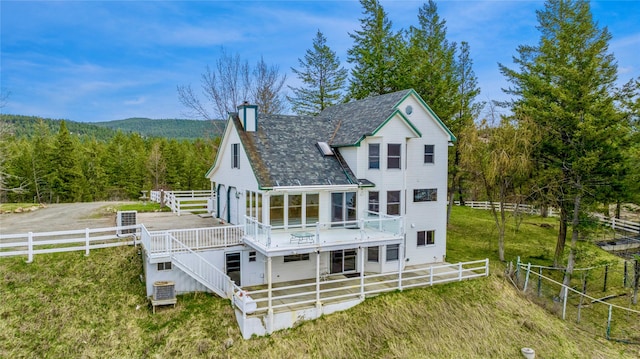 7100 Black Lake Rd, Rexford, MT 59930 - rear view of property featuring a chimney, a wooded view, a deck, and a fenced backyard