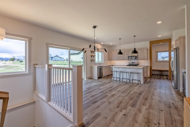 5498 Thimbleberry Loop, Helena, MT 59602 - kitchen with a center island, light countertops, light wood-style flooring, appliances with stainless steel finishes, and backsplash