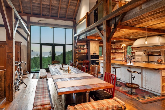dining space with high vaulted ceiling, beamed ceiling, a mountain view, and hardwood / wood-style floors