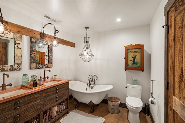 bathroom featuring a sink, a freestanding tub, visible vents, and wood finished floors