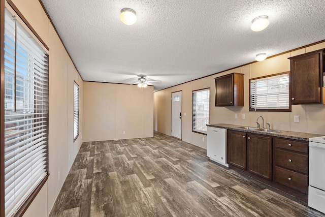 kitchen with white appliances, a textured ceiling, dark wood finished floors, and a sink