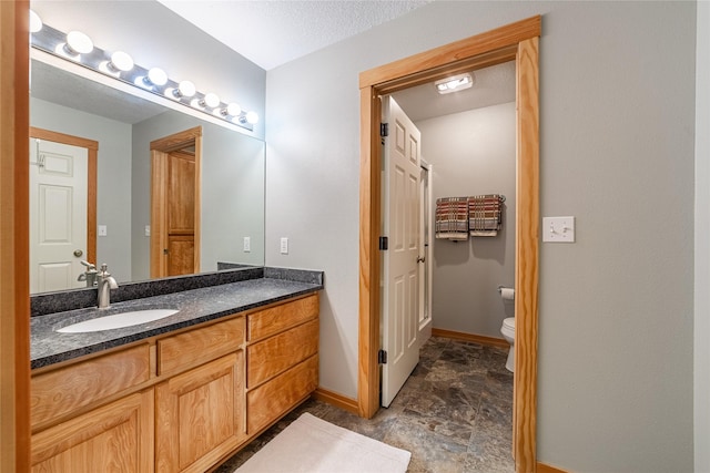 107 Crescent Lndg, Polson, MT 59860 - bathroom with baseboards, vanity, stone finish flooring, and toilet