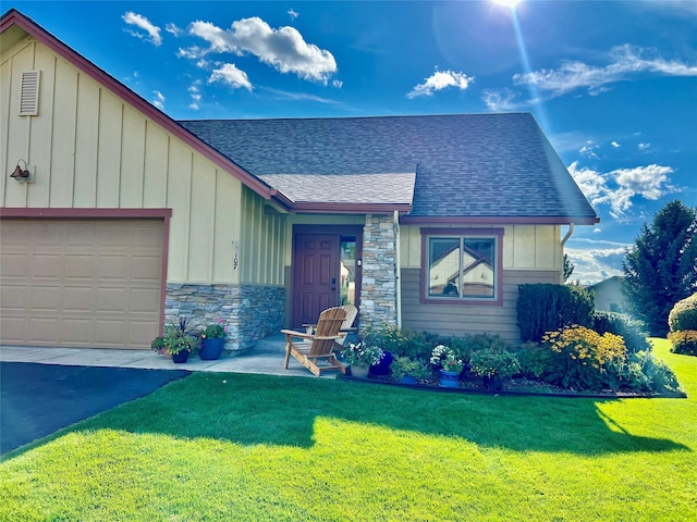 107 Crescent Lndg, Polson, MT 59860 - view of front of property featuring a garage, a front yard, stone siding, roof with shingles, and board and batten siding