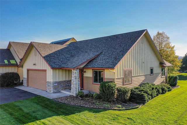 107 Crescent Lndg, Polson, MT 59860 - view of front of house featuring a front lawn, a shingled roof, board and batten siding, an attached garage, and driveway