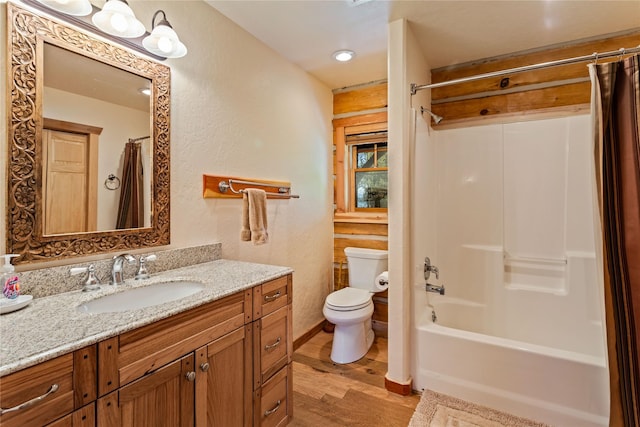 bathroom with a textured wall, vanity, toilet, shower / bath combination with curtain, and wood finished floors