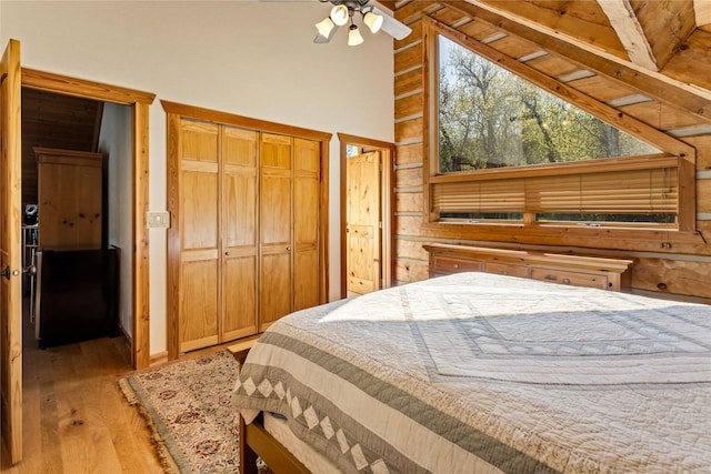 bedroom featuring high vaulted ceiling, light wood finished floors, and a closet