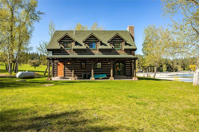 back of house featuring a shingled roof, a chimney, a lawn, and a water view