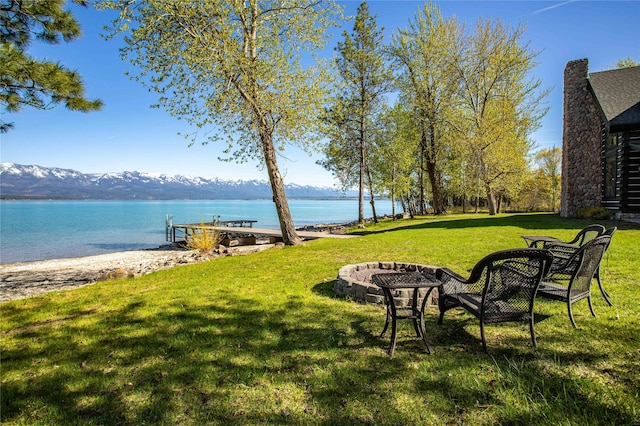 view of yard featuring a water and mountain view and a fire pit