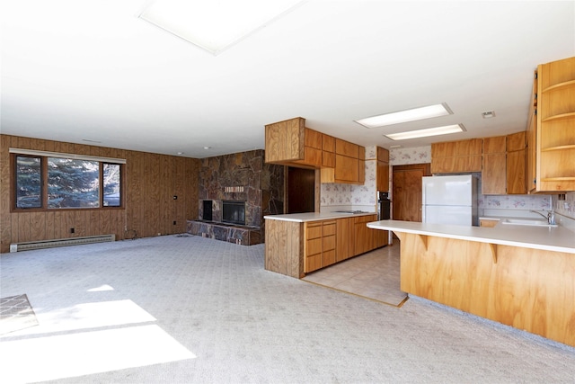 kitchen with open shelves, baseboard heating, a sink, freestanding refrigerator, and a peninsula