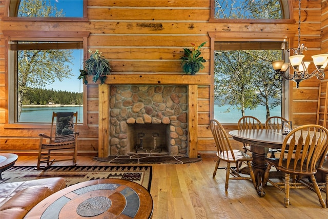 dining space with wood-type flooring, wooden walls, a notable chandelier, and a fireplace
