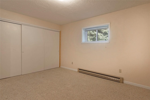 unfurnished bedroom featuring a closet, carpet floors, baseboards, baseboard heating, and a textured ceiling