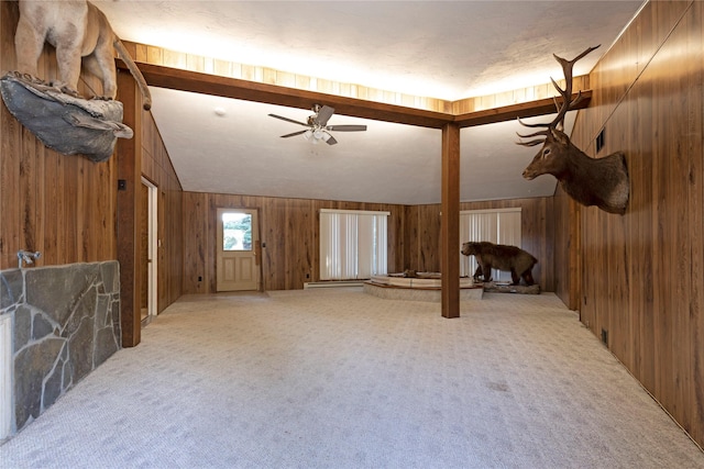 unfurnished living room featuring wooden walls, ceiling fan, lofted ceiling, and light colored carpet