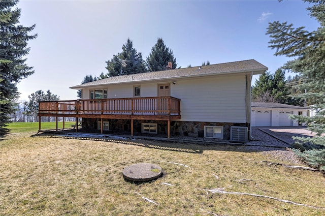 rear view of property featuring a lawn, a detached garage, a wooden deck, and central air condition unit