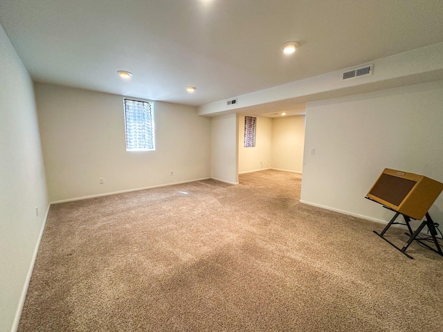 basement with baseboards, visible vents, and light carpet