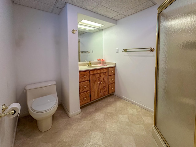 bathroom featuring baseboards, tile patterned floors, a drop ceiling, and toilet