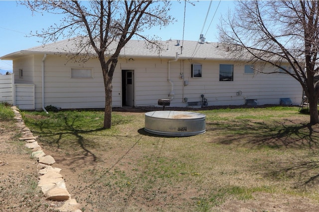 rear view of property featuring a lawn and a shingled roof