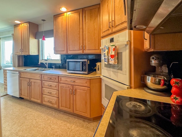 kitchen featuring white appliances, recessed lighting, light countertops, a sink, and hanging light fixtures