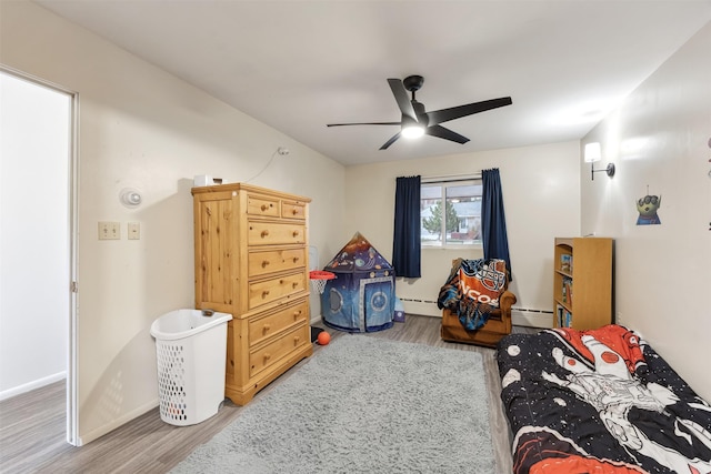 bedroom featuring baseboards, a ceiling fan, a baseboard heating unit, and wood finished floors