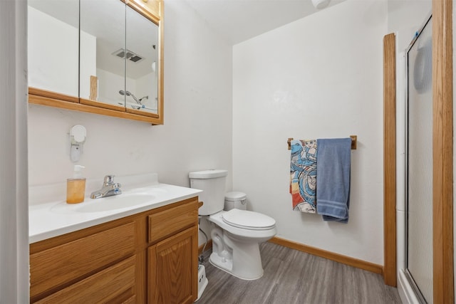full bathroom featuring vanity, a shower with shower door, toilet, and wood finished floors