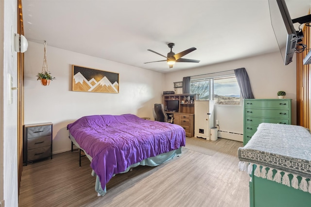 bedroom featuring wood finished floors, ceiling fan, and a baseboard heating unit